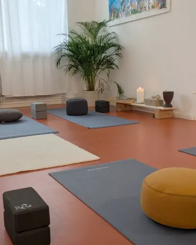 Das Studio mit ausgelegten Yogamatten, Meditationskissen und Kerze