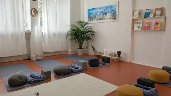 Der Kursraum mit sechs aufgebauten Yogamatten, Decken und Meditationskissen
